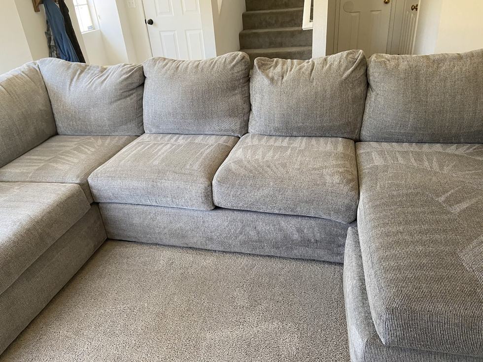 A large sectional sofa in light gray fabric, cleaned, with the cushions back in place.