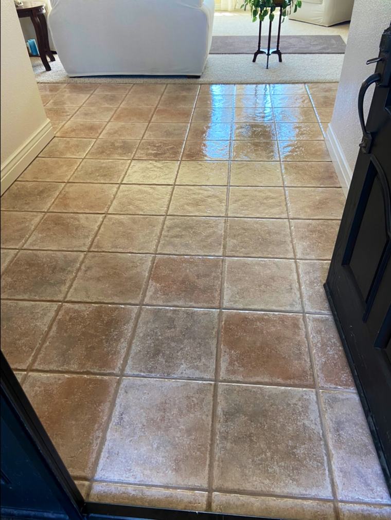 A terracotta tile floor after cleaning, the grout lines even and the surface reflecting the light.